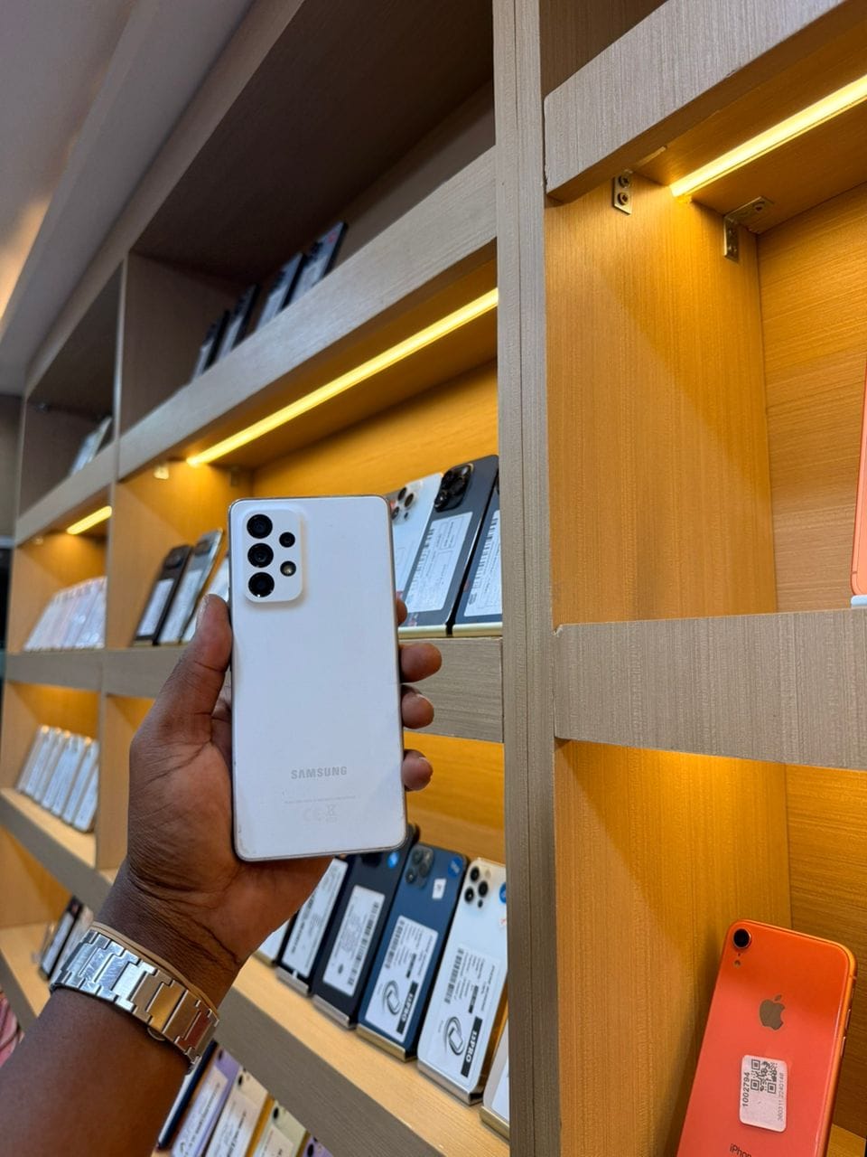 Samsung Galaxy A53 blanc, vu de dos, tenu en main dans la boutique