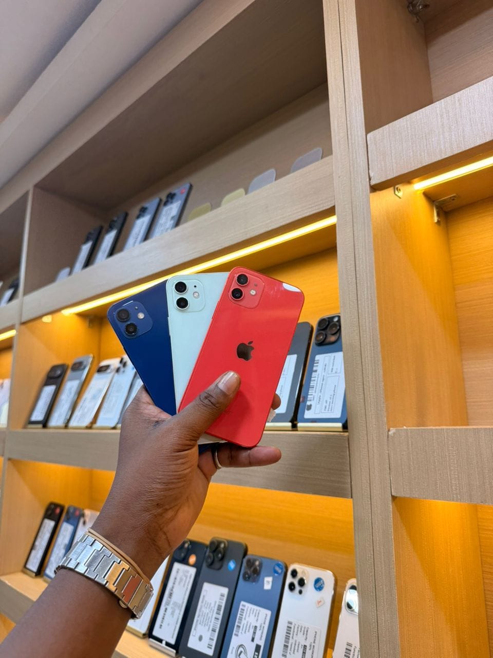 Trois iPhone 12, bleu, vert et rouge, vus de dos, tenus en main