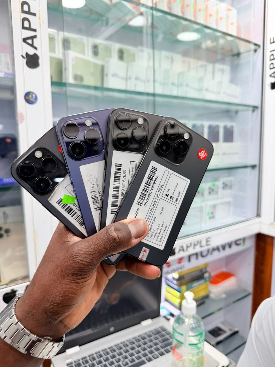 Quatre iPhone 14 Pro noirs et violet, vus de dos, tenus en main