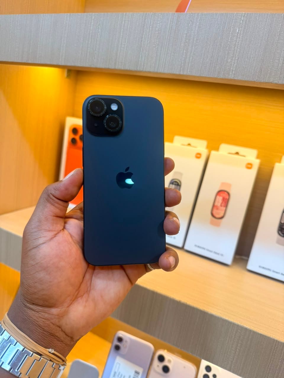 iPhone 15 noir, vu de dos, tenu en main dans la boutique