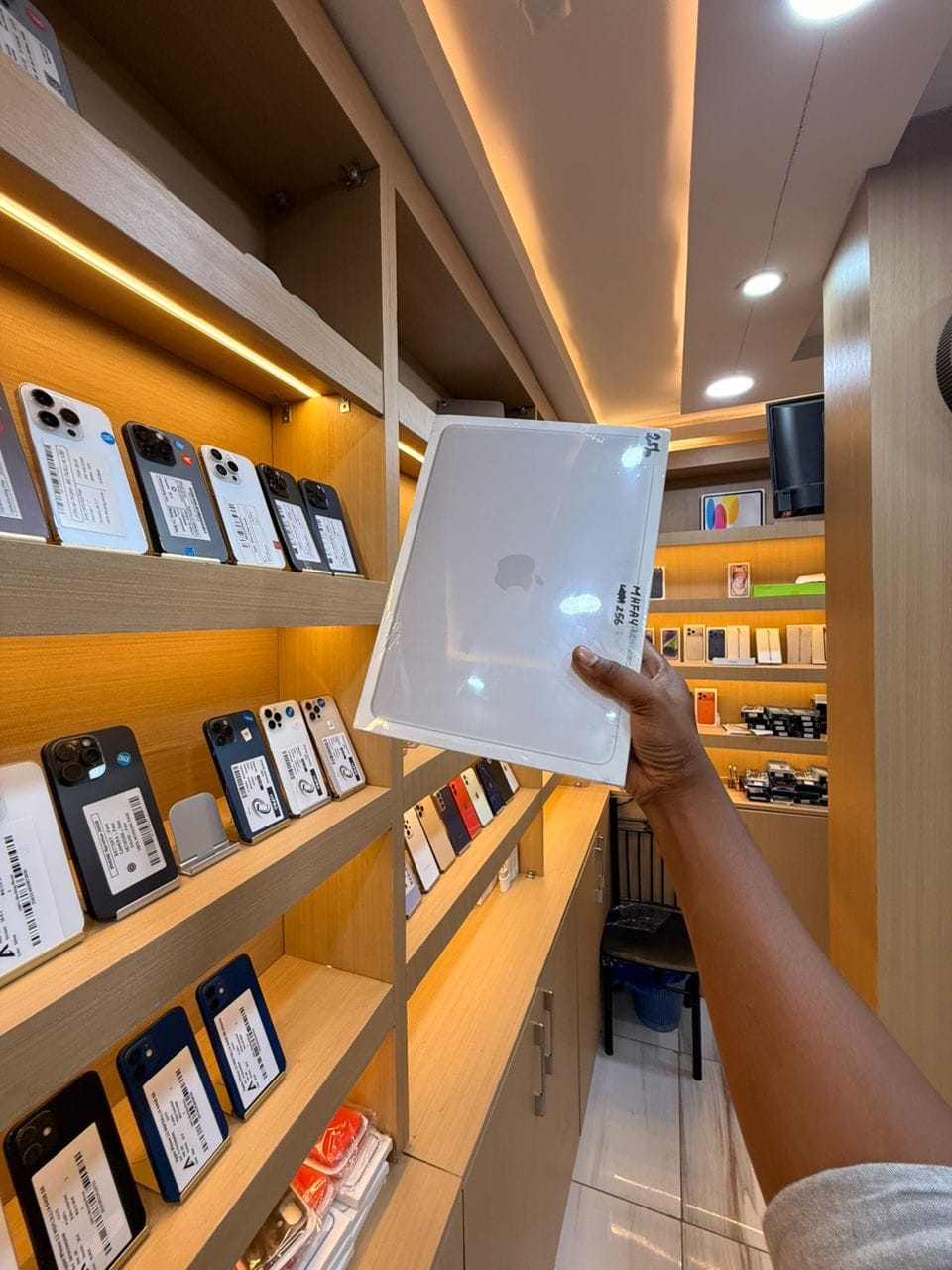 MacBook Neo scellé sous blister, tenu en main dans la boutique